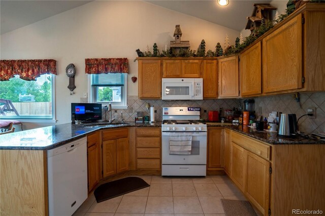 kitchen featuring white appliances, lofted ceiling, a peninsula, light tile patterned floors, and a sink