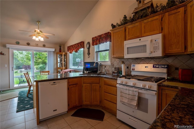 kitchen featuring white appliances, a sink, vaulted ceiling, a peninsula, and backsplash