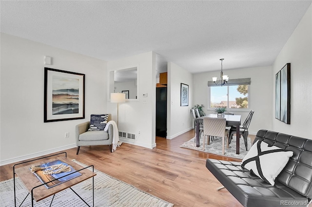 9946 Harrison St, Thornton, CO 80229 - living room with a chandelier, light wood-style flooring, baseboards, and a textured ceiling
