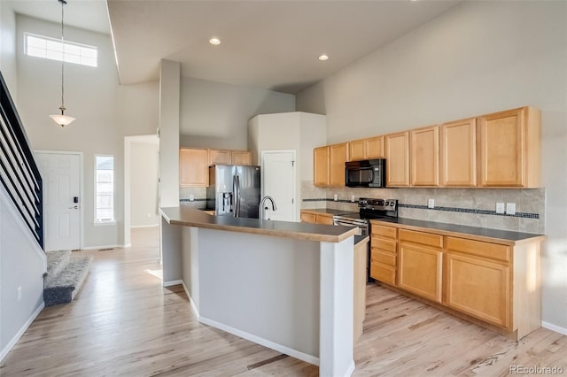 kitchen with a high ceiling, backsplash, light brown cabinets, and appliances with stainless steel finishes