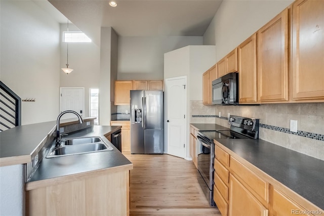 kitchen featuring light wood finished floors, a sink, light brown cabinetry, black appliances, and a kitchen island with sink