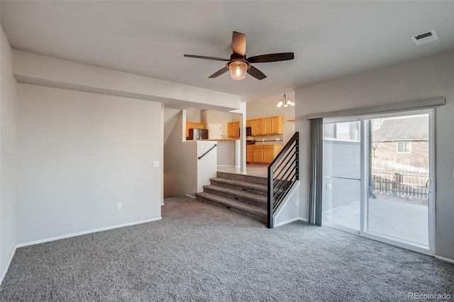 unfurnished living room featuring visible vents, baseboards, stairs, carpet flooring, and ceiling fan with notable chandelier