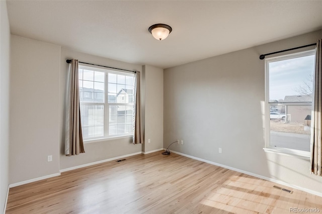 spare room with visible vents, baseboards, and wood finished floors