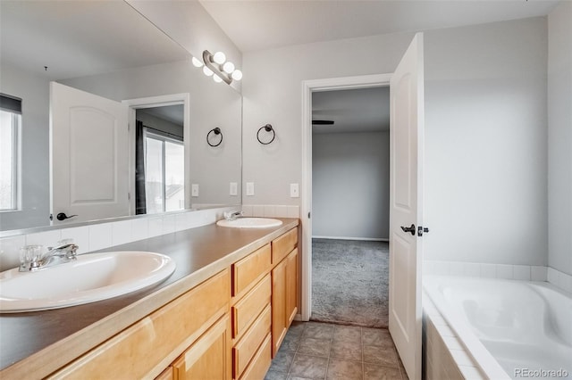 bathroom with double vanity, a wealth of natural light, a relaxing tiled tub, and a sink