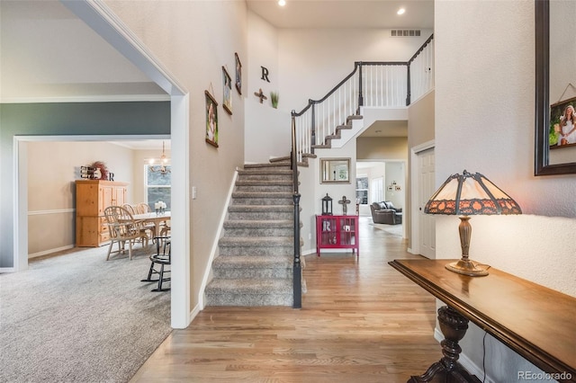 foyer with a towering ceiling, a chandelier, and light wood-type flooring