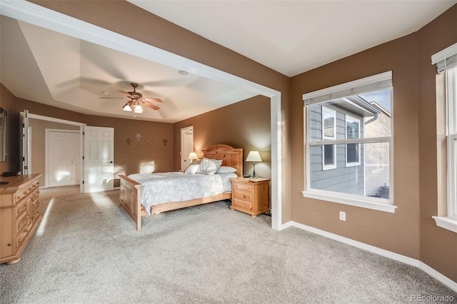 bedroom featuring ceiling fan, light colored carpet, and a raised ceiling