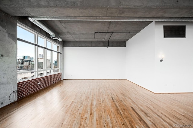 unfurnished room with wood-type flooring and brick wall