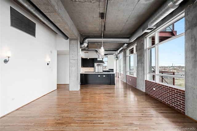 interior space with light hardwood / wood-style floors and brick wall