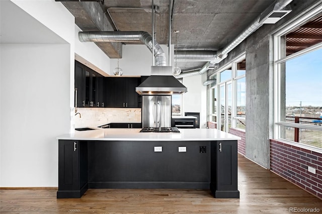 kitchen with sink, hanging light fixtures, kitchen peninsula, appliances with stainless steel finishes, and hardwood / wood-style flooring