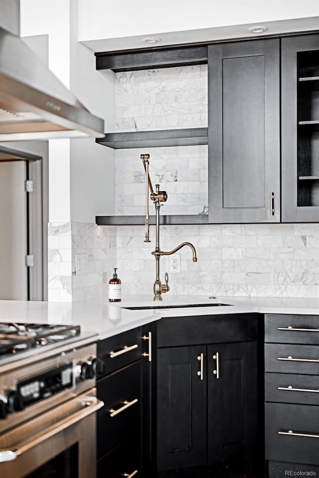 kitchen featuring stainless steel range with gas cooktop, sink, wall chimney range hood, and backsplash