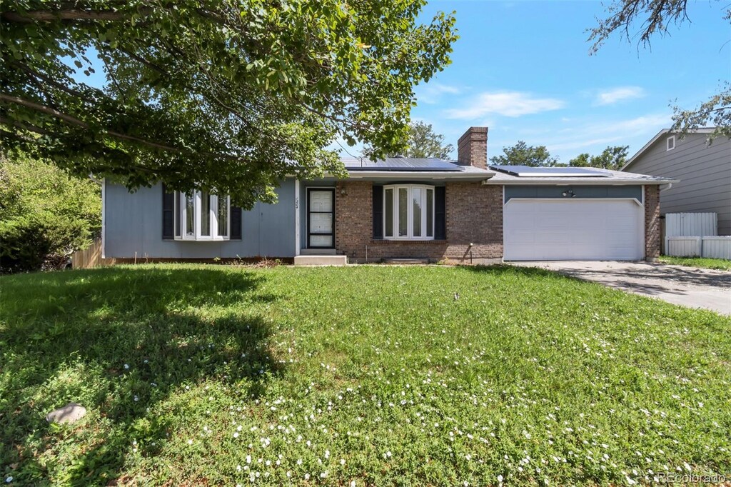 1204 S Salida Way, Aurora, CO 80017 - view of front facade with concrete driveway, a chimney, an attached garage, solar panels, and brick siding