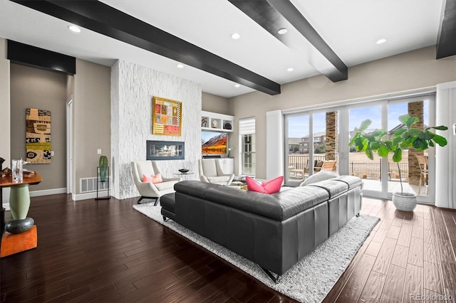 living area featuring recessed lighting, visible vents, dark wood-type flooring, a glass covered fireplace, and beamed ceiling