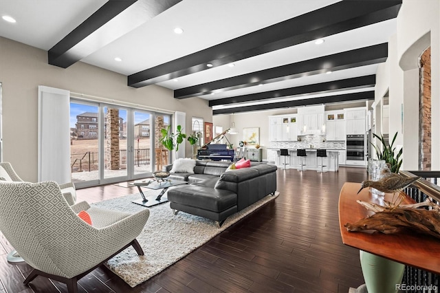 living area with dark wood-style floors, a city view, beamed ceiling, and recessed lighting