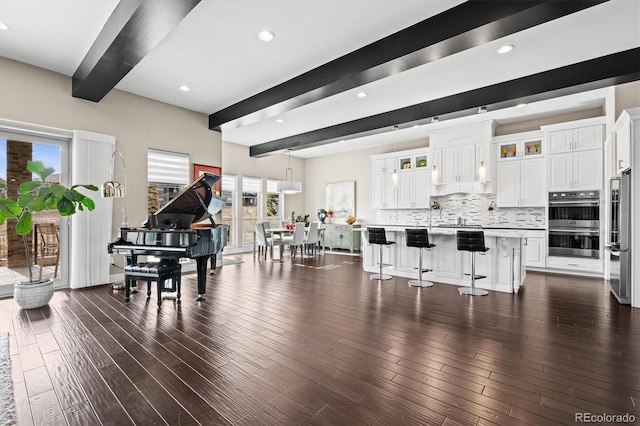 living room featuring dark wood-style flooring, beamed ceiling, and recessed lighting