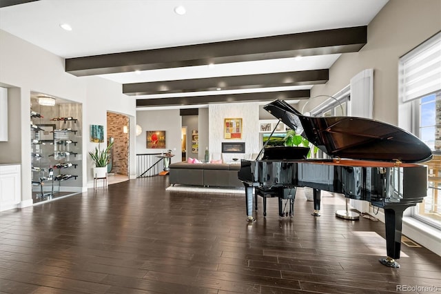 misc room with recessed lighting, dark wood-type flooring, a fireplace, an upstairs landing, and beam ceiling