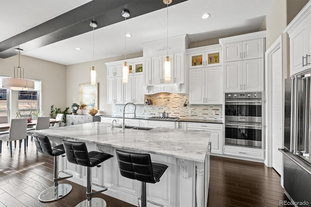 kitchen featuring glass insert cabinets, stainless steel appliances, white cabinetry, and hanging light fixtures