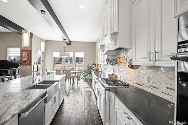 kitchen with tasteful backsplash, dark stone counters, appliances with stainless steel finishes, decorative light fixtures, and white cabinetry