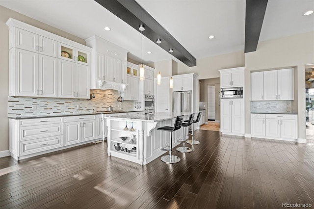 kitchen featuring a center island with sink, open shelves, appliances with stainless steel finishes, glass insert cabinets, and white cabinetry