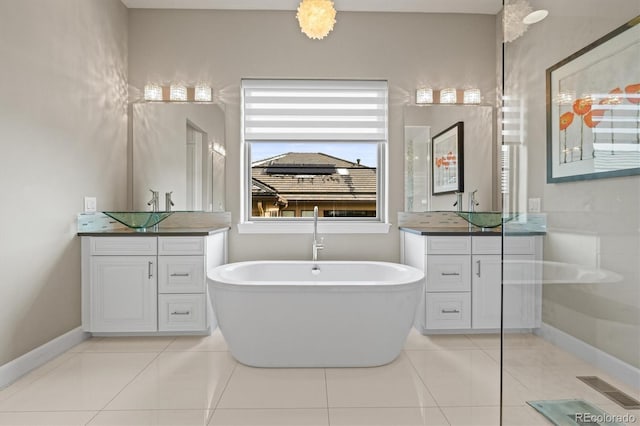 full bath featuring two vanities, visible vents, a freestanding bath, a sink, and tile patterned flooring