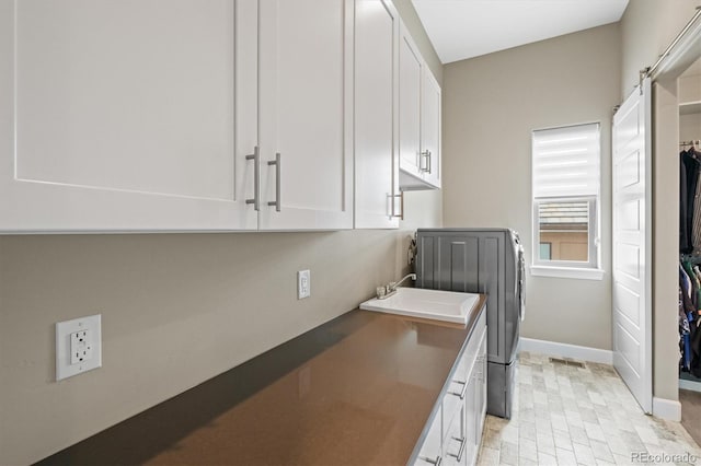 laundry room featuring cabinet space, visible vents, baseboards, independent washer and dryer, and a sink