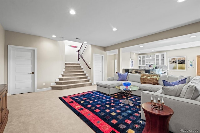 living area featuring recessed lighting, light colored carpet, stairway, and baseboards