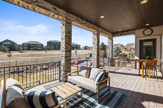 view of patio featuring exterior kitchen, a residential view, a grill, and an outdoor living space