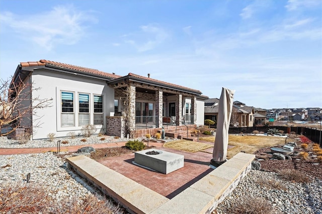 view of front of home with an outdoor fire pit, a tile roof, a patio, and stucco siding