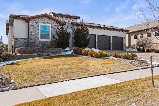 view of front of house featuring driveway, stone siding, a tile roof, an attached garage, and stucco siding