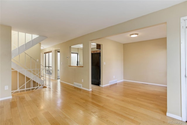 unfurnished room with stairway, baseboards, visible vents, and light wood-type flooring