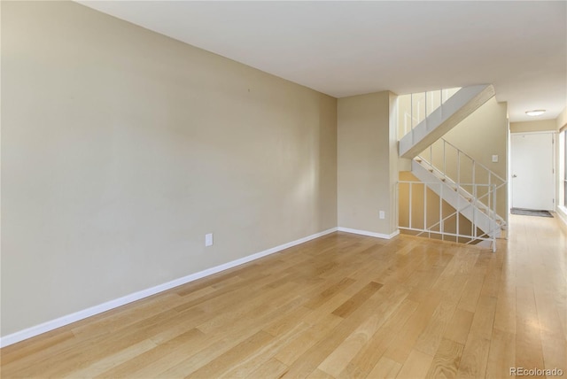 spare room with stairs, baseboards, and light wood-type flooring