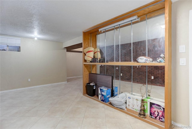 finished basement with tile patterned flooring, a textured ceiling, and baseboards