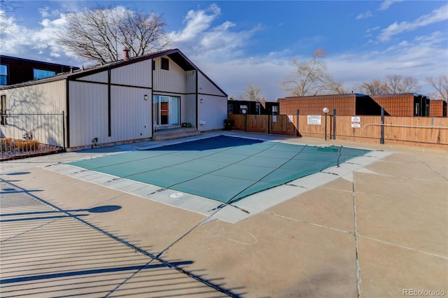 community pool with a patio area and fence