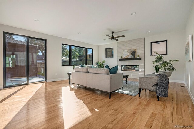 living room with a fireplace, light hardwood / wood-style flooring, and ceiling fan