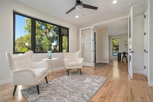 living area featuring french doors, light wood-type flooring, and ceiling fan