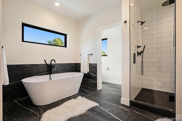 bathroom featuring independent shower and bath, a healthy amount of sunlight, and tile walls