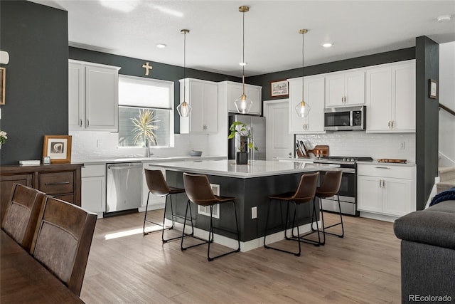 kitchen featuring a kitchen breakfast bar, open floor plan, white cabinetry, backsplash, and appliances with stainless steel finishes