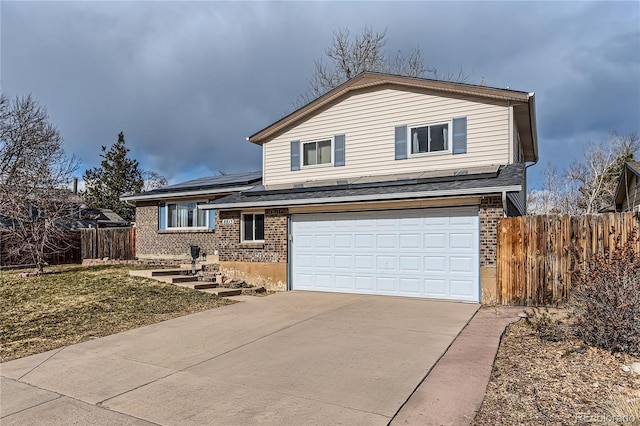 split level home featuring brick siding, fence, driveway, and an attached garage