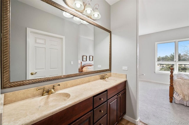 ensuite bathroom featuring double vanity, ensuite bath, baseboards, and a sink