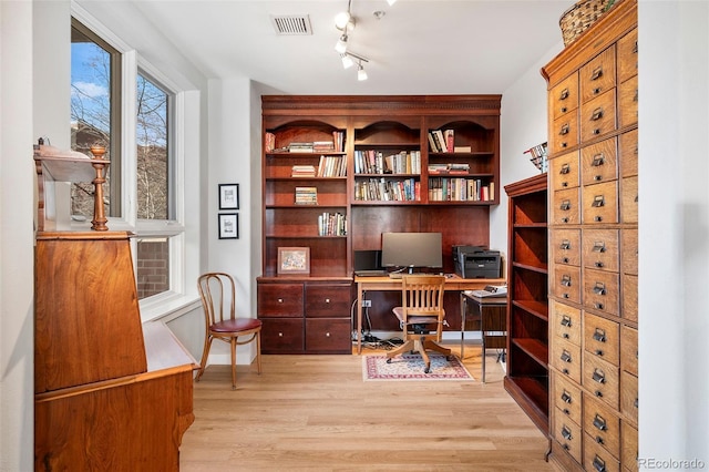 home office featuring light wood-type flooring and visible vents