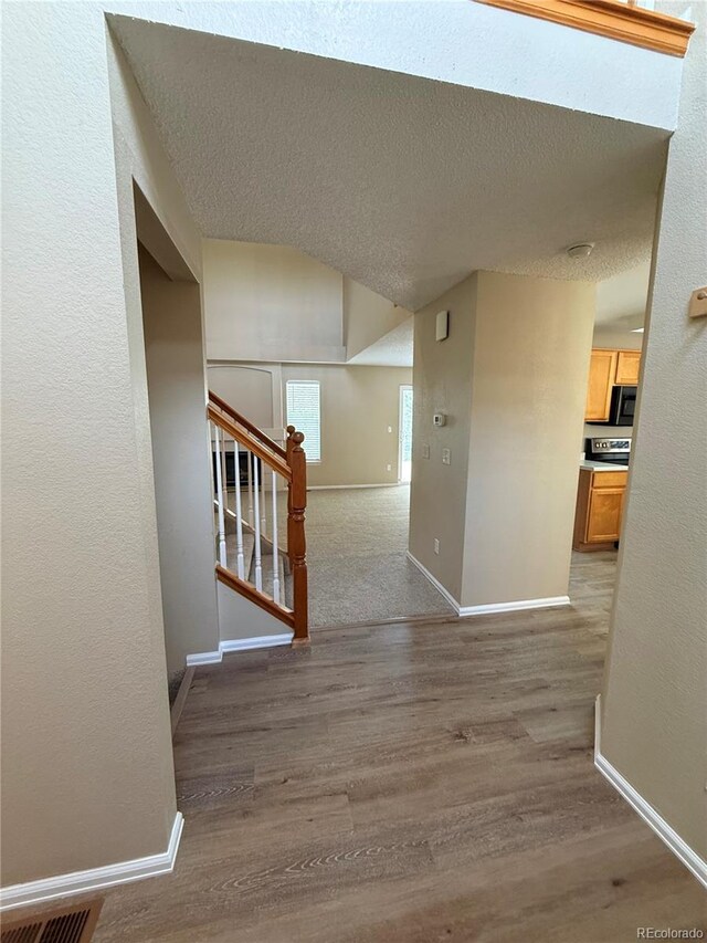 23760 Broadmoor Dr, Parker, CO 80138 - hall with light wood-style flooring, baseboards, stairs, a textured ceiling, and vaulted ceiling