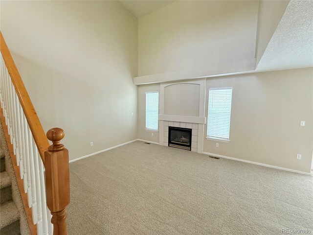 23760 Broadmoor Dr, Parker, CO 80138 - unfurnished living room with baseboards, carpet, a fireplace, stairway, and a towering ceiling