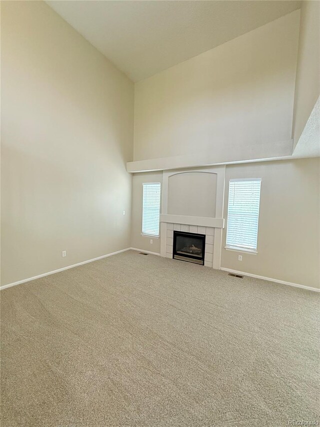 23760 Broadmoor Dr, Parker, CO 80138 - unfurnished living room featuring high vaulted ceiling, carpet flooring, baseboards, and a tiled fireplace