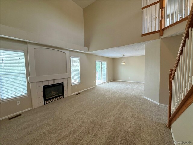 23760 Broadmoor Dr, Parker, CO 80138 - unfurnished living room with carpet, a tiled fireplace, high vaulted ceiling, baseboards, and stairway