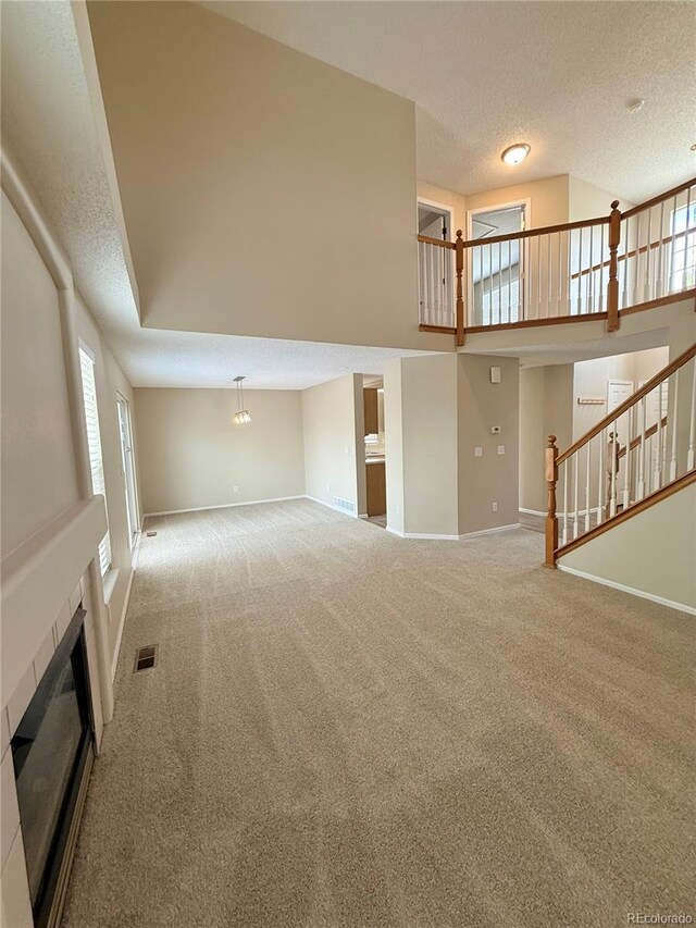 23760 Broadmoor Dr, Parker, CO 80138 - unfurnished living room featuring carpet floors, a textured ceiling, baseboards, a fireplace, and stairway