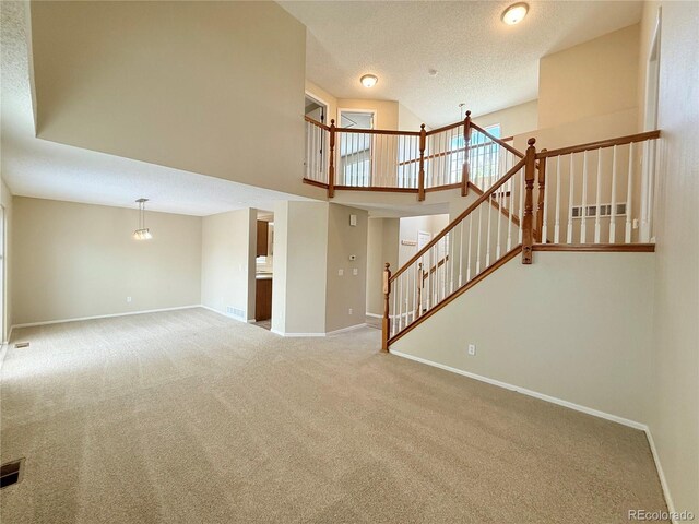23760 Broadmoor Dr, Parker, CO 80138 - unfurnished living room with carpet, baseboards, stairs, a high ceiling, and a textured ceiling