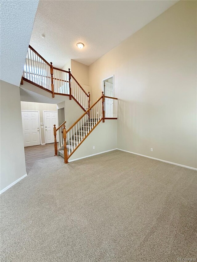 23760 Broadmoor Dr, Parker, CO 80138 - unfurnished living room with carpet flooring, baseboards, stairs, a textured ceiling, and vaulted ceiling