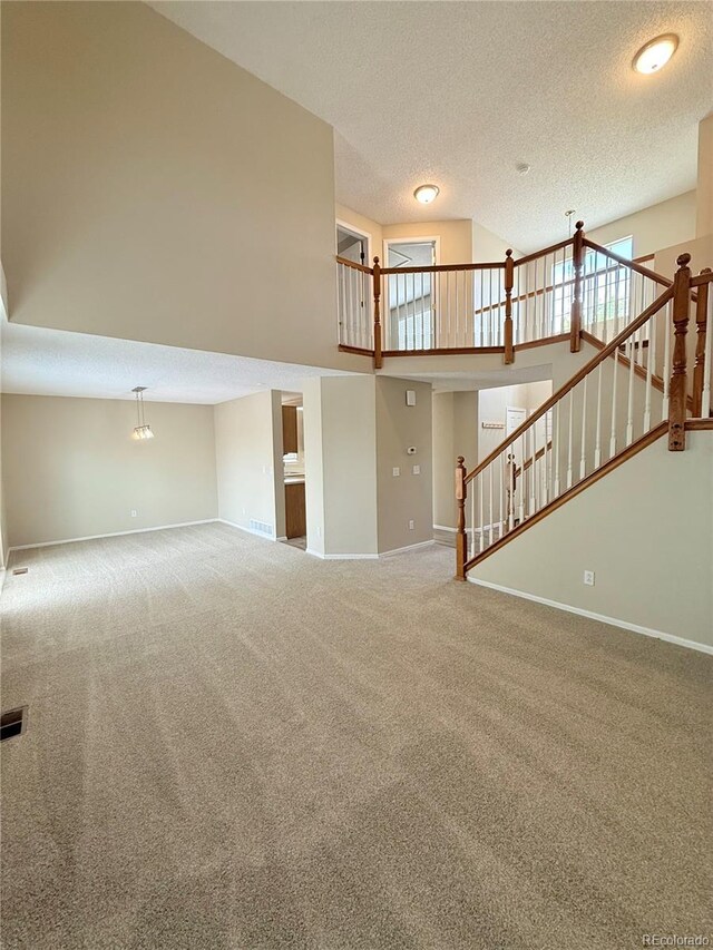 23760 Broadmoor Dr, Parker, CO 80138 - unfurnished living room with carpet flooring, baseboards, a textured ceiling, a high ceiling, and stairway
