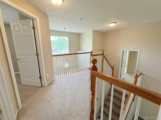 23760 Broadmoor Dr, Parker, CO 80138 - hallway featuring light carpet, an upstairs landing, and a textured ceiling