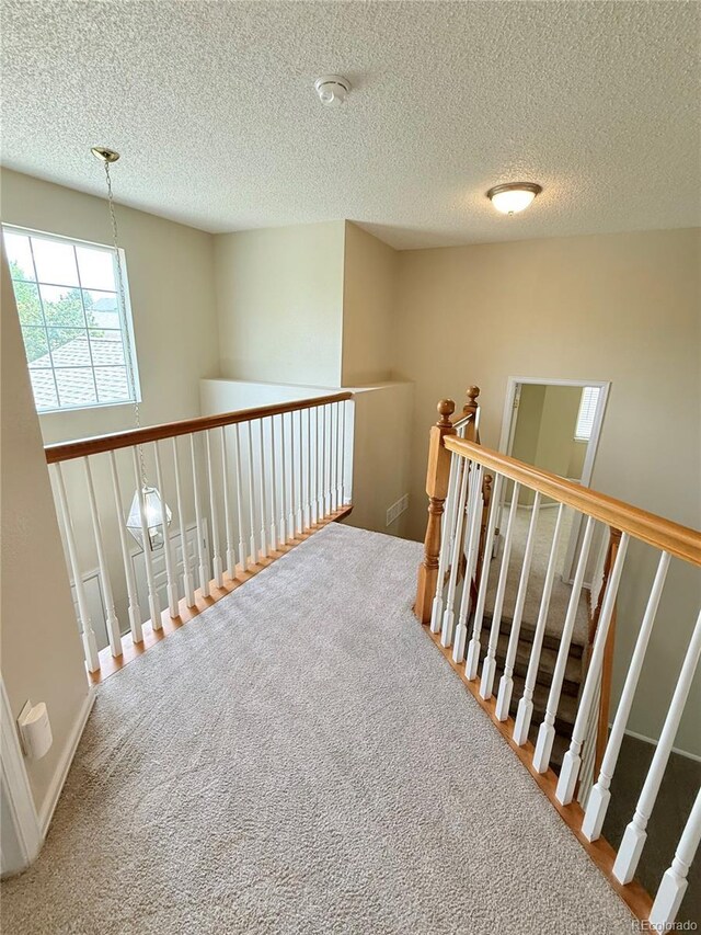 23760 Broadmoor Dr, Parker, CO 80138 - hallway featuring a textured ceiling, carpet flooring, and an upstairs landing
