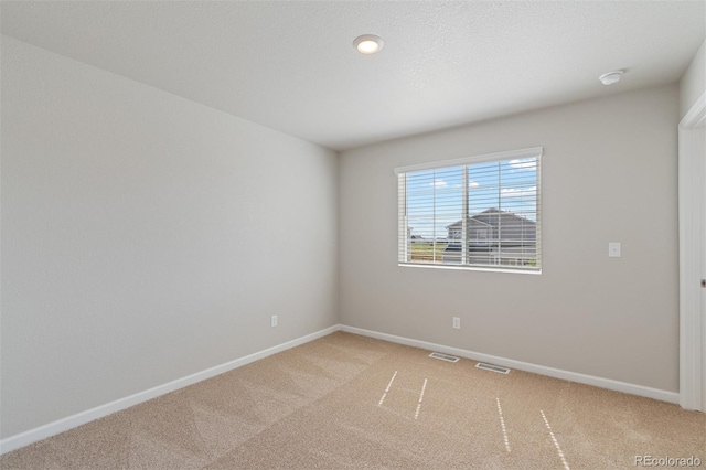 empty room with baseboards, visible vents, and light carpet